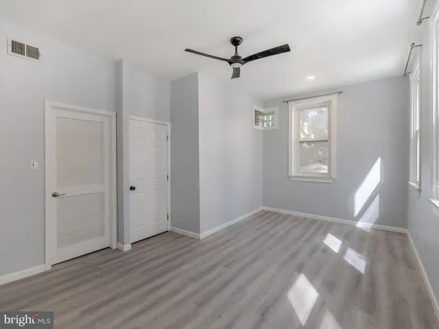 a view of empty room with wooden floor and fan
