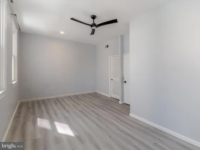 an empty room with wooden floor and a ceiling fan