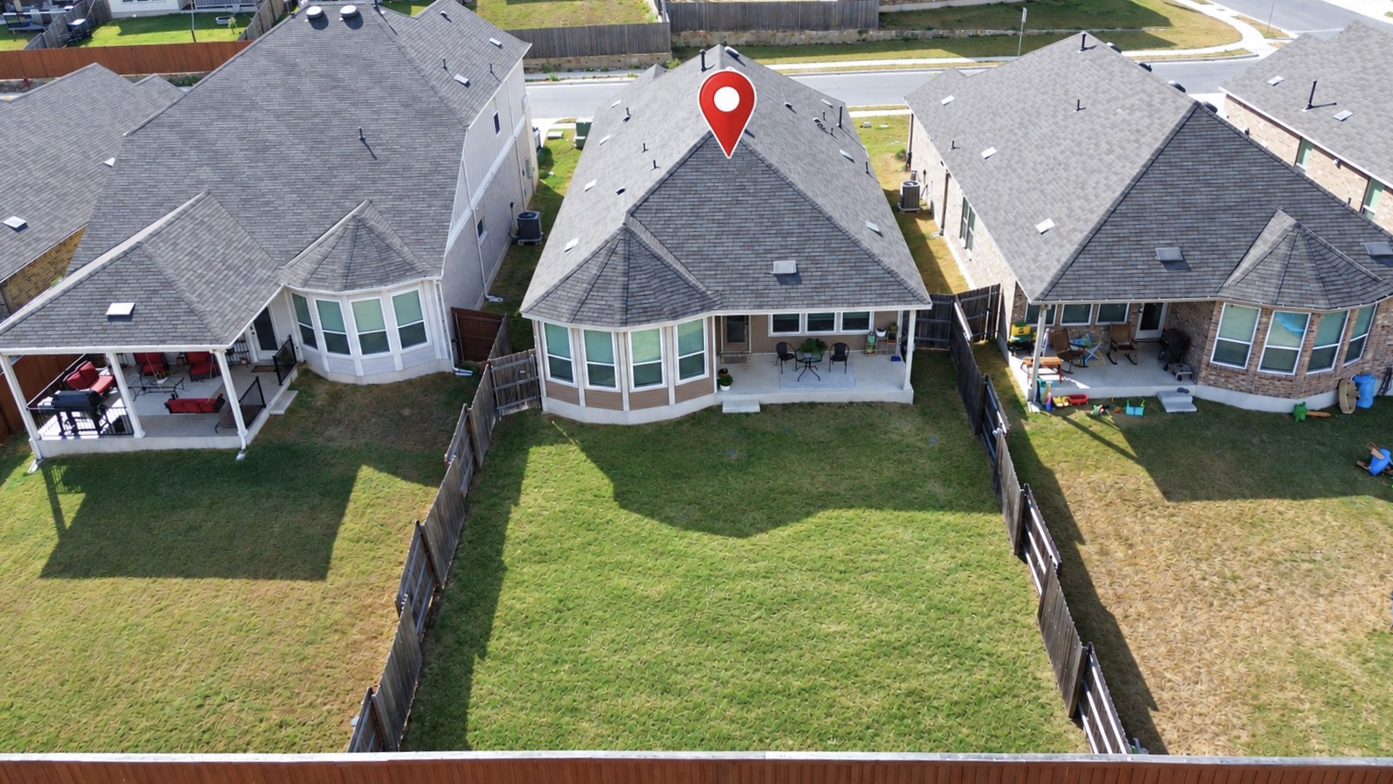 181 Tree Nut Loop Buda, TX 78610 - Photo 26 of 33 An aerial perspective showcases a spacious backyard enclosed by wooden fencing.