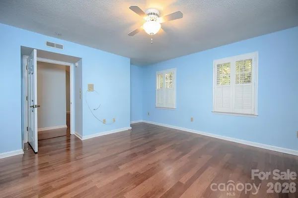 an empty room with wooden floor and a ceiling fan
