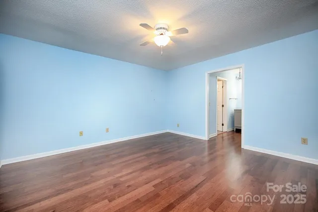an empty room with wooden floor and a ceiling fan