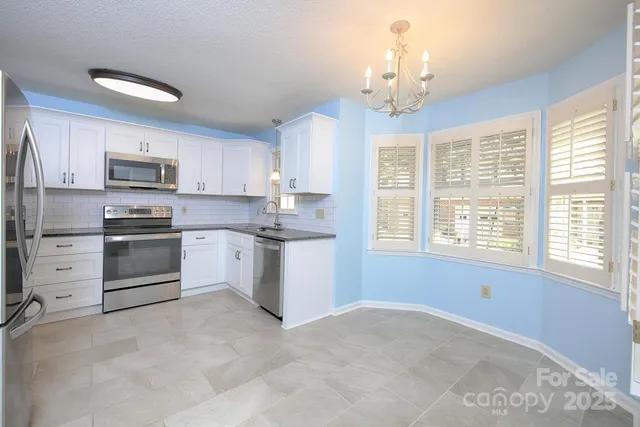 a kitchen with stainless steel appliances a stove a sink dishwasher a refrigerator and a microwave