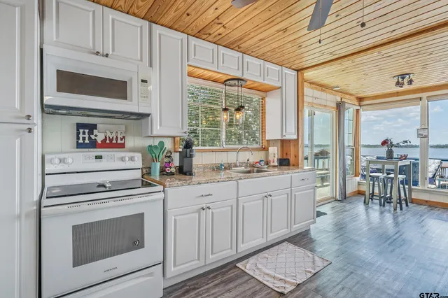 a kitchen with granite countertop a stove a sink and a microwave