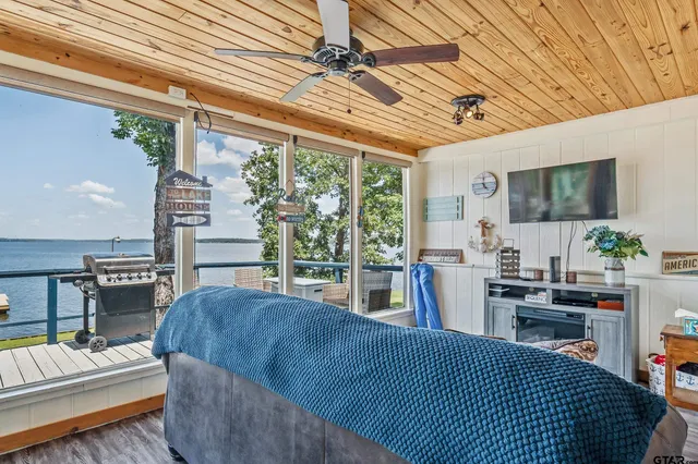 a living room with furniture a flat screen tv and floor to ceiling window