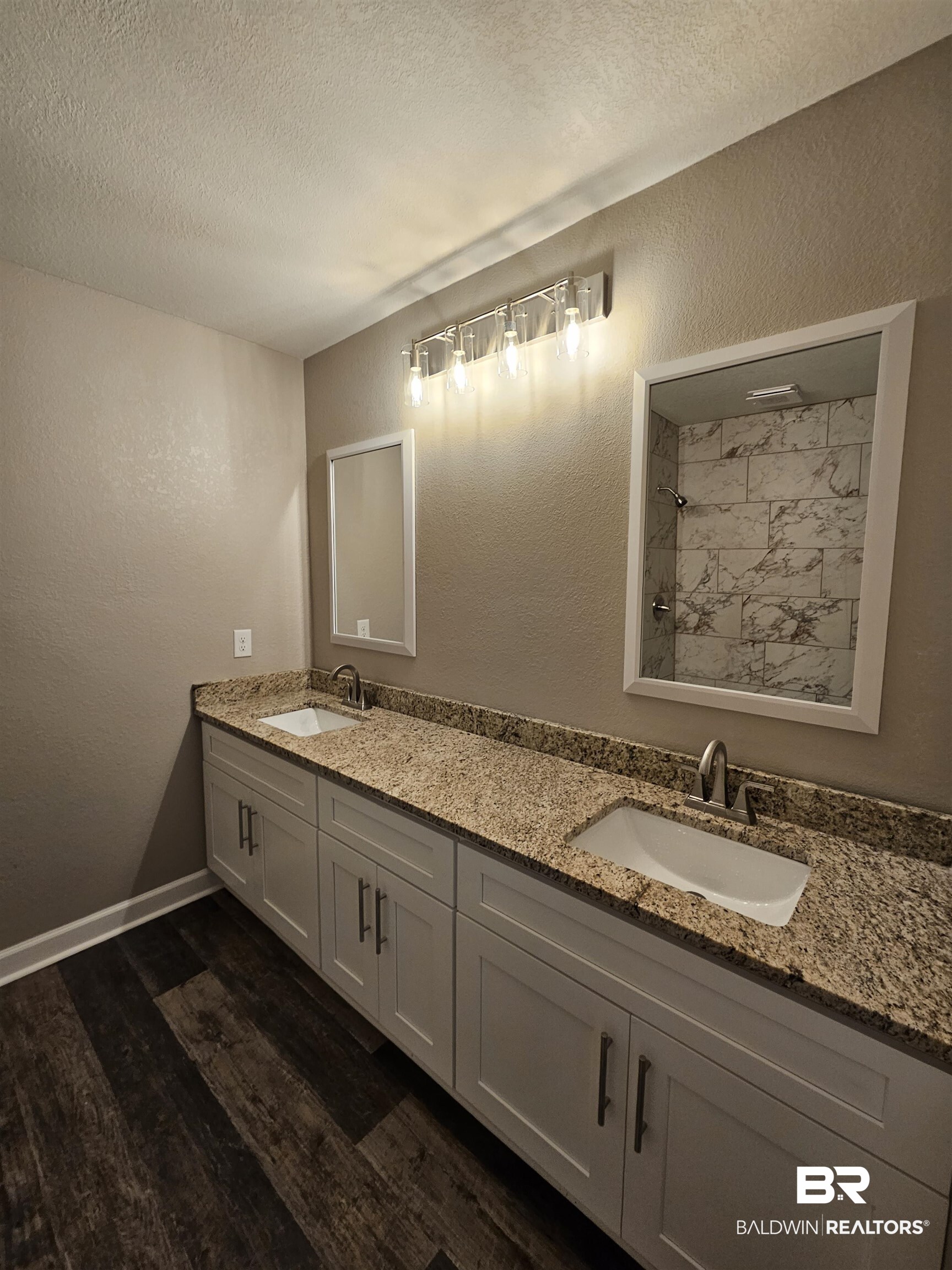 138 Wicker Way Daphne, AL 36526 - Photo 26 of 32 Bathroom with a textured wall, double vanity, dark wood-type flooring, a textured ceiling, and a tile shower