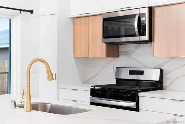 a kitchen with stainless steel appliances granite countertop a sink and a stove top oven with wooden floor