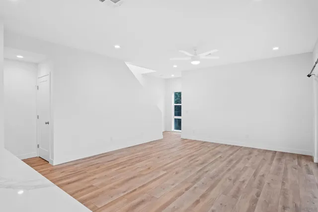 a view of an empty room with wooden floor and a window