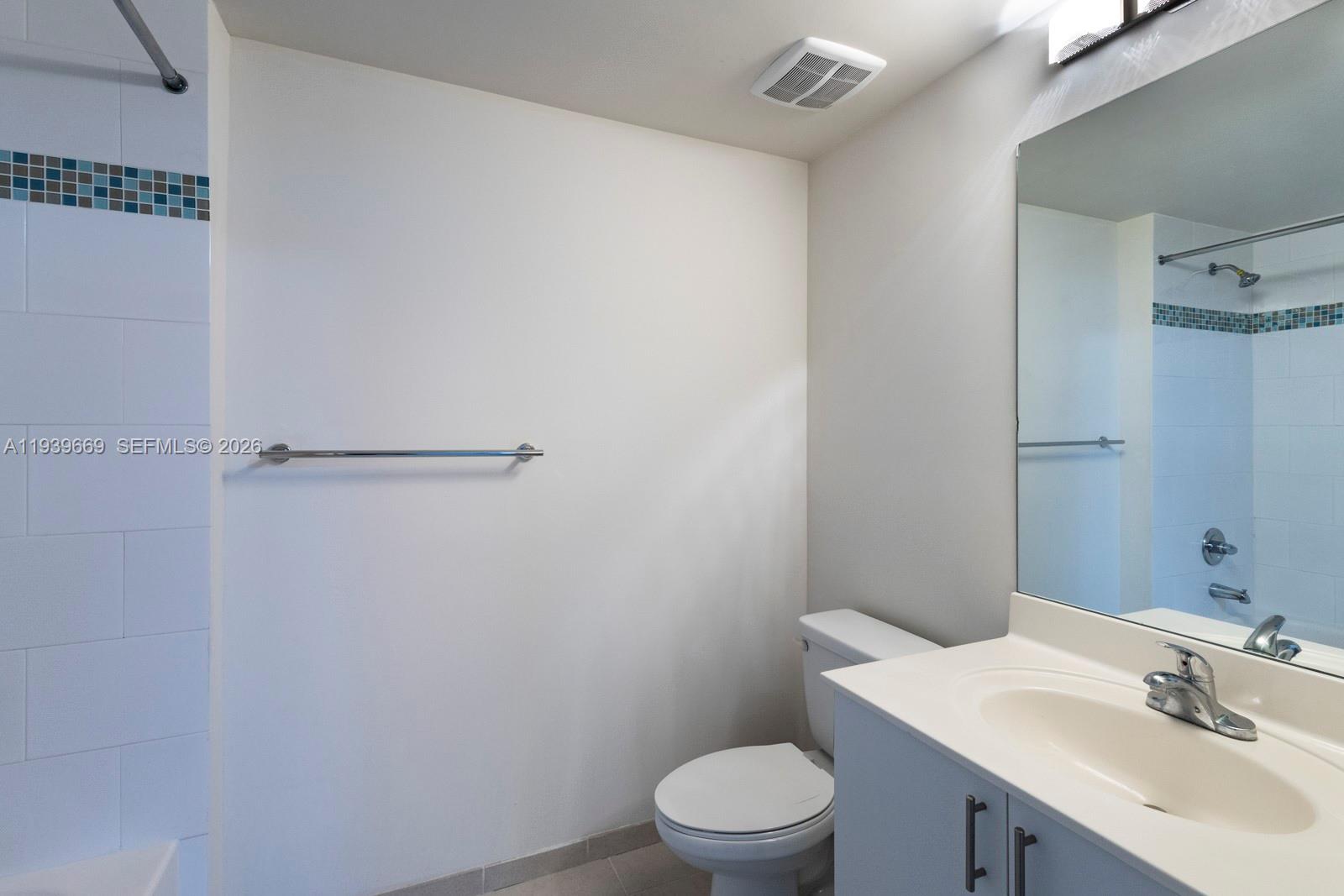 2350 Southwest 27th Avenue, Unit 809 Miami, FL 33145 - Photo 10 of 21 a bathroom with a toilet a sink and mirror