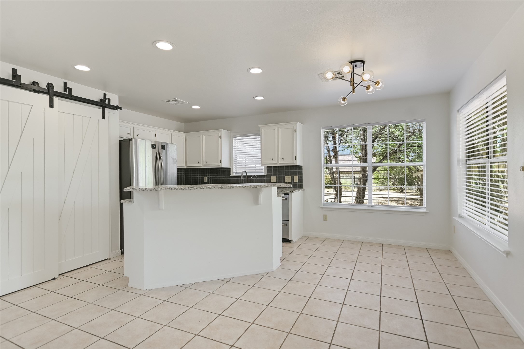 104 Crazy Cross Road Wimberley, TX 78676 - Photo 6 of 20 Tiled flooring flows through this airy kitchen and adjacent breakfast area under recessed lighting.