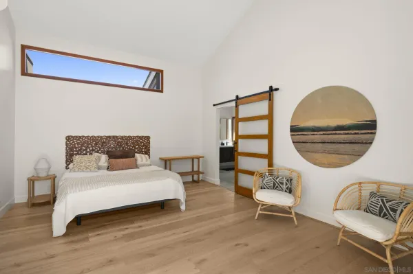 a bedroom with a bed a chair and a wooden floor