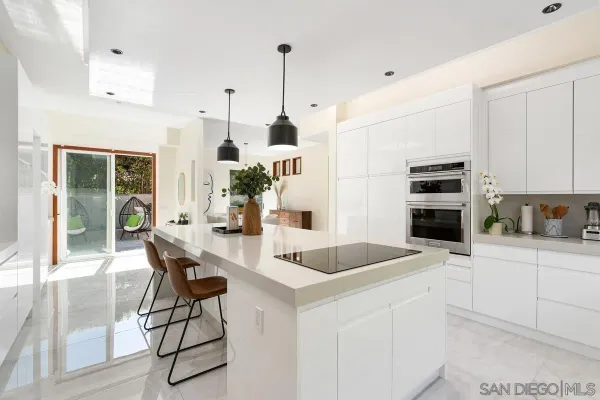 a kitchen with stainless steel appliances kitchen island granite countertop a table chairs and a refrigerator