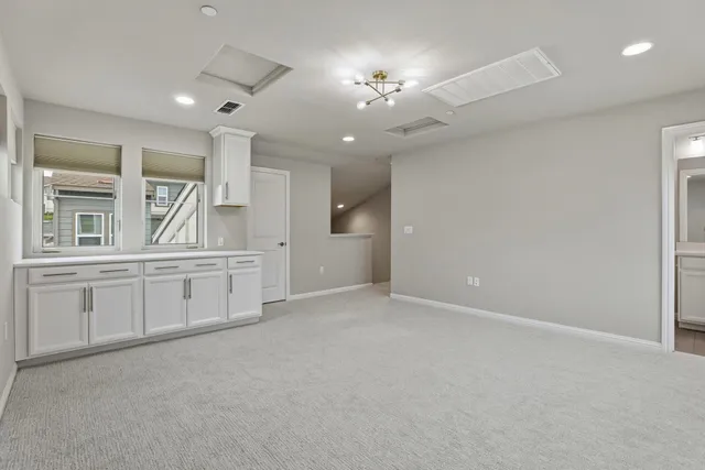 an empty room with chandelier fan and windows