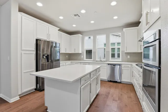 a kitchen with white cabinets and stainless steel appliances