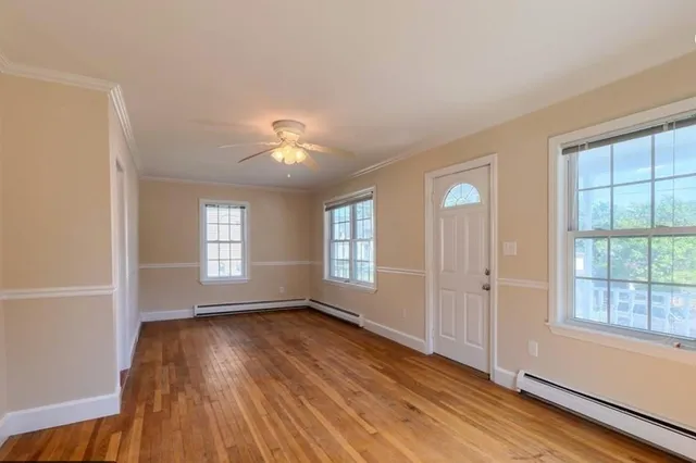 a view of an empty room with wooden floor and a window