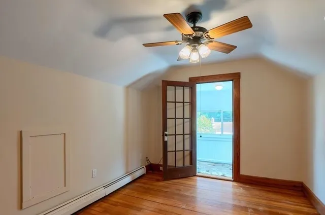 an empty room with wooden floor chandelier fan and windows