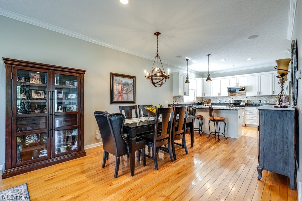 6325 Brecksville Road Independence, OH 44131 - Photo 13 of 50 The property features an open concept kitchen and dining area, showcasing hardwood flooring, a dining table with seating, and a kitchen island with bar seating