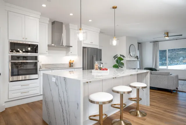 a kitchen with kitchen island stainless steel appliances a dining table chairs sink and cabinets