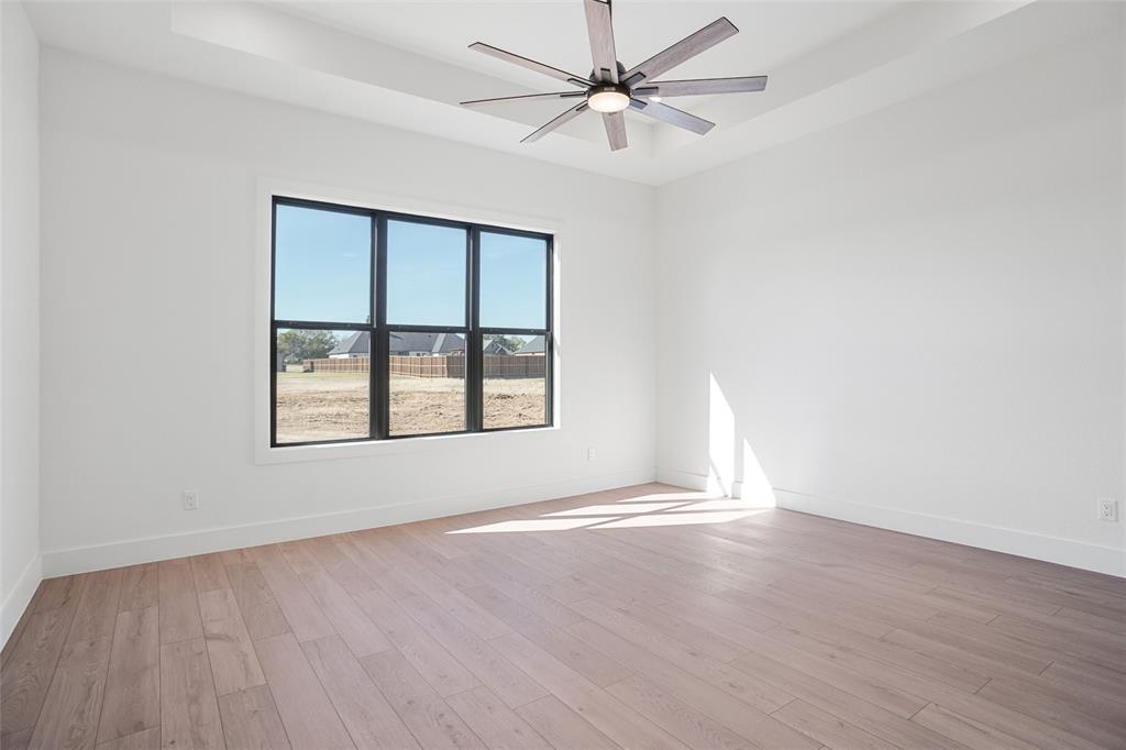 207 Stuart Street Paradise, TX 76073 - Photo 15 of 30 an empty room with wooden floor fan and windows
