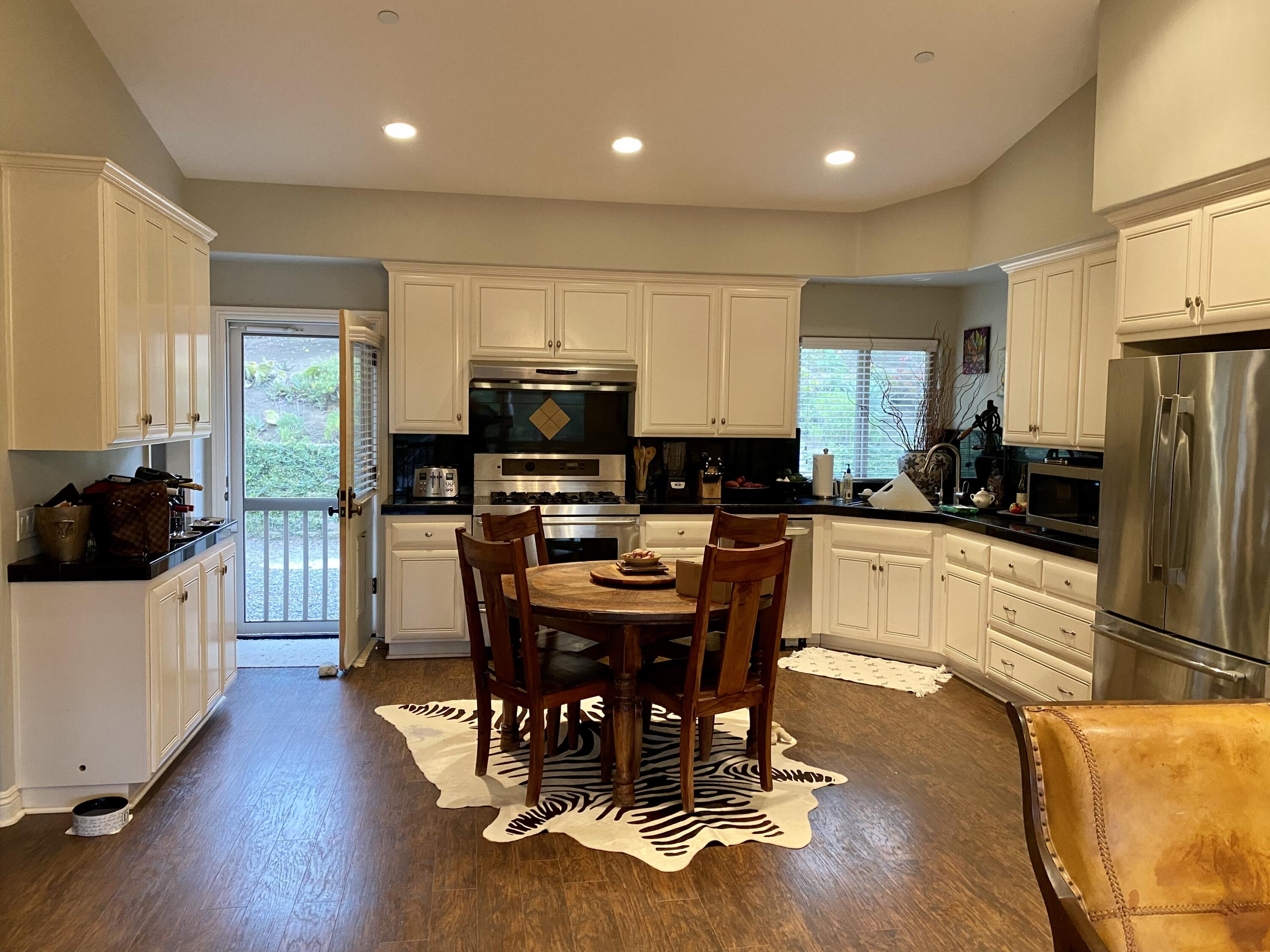 3705 La Canada Road Fallbrook, CA 92028 - Photo 22 of 68 a kitchen with stainless steel appliances kitchen island granite countertop a stove a refrigerator a sink a dining table and chairs with wooden floor