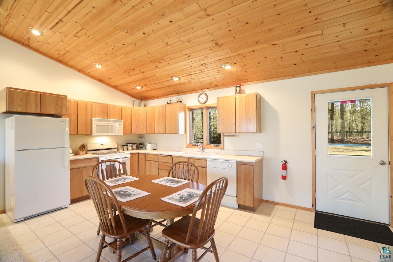 1880 Everett Bay Road Tower, MN 55790 - Photo 32 of 50 Kitchen featuring white appliances, vaulted ceiling, wood ceiling, light tile patterned flooring, and light countertops