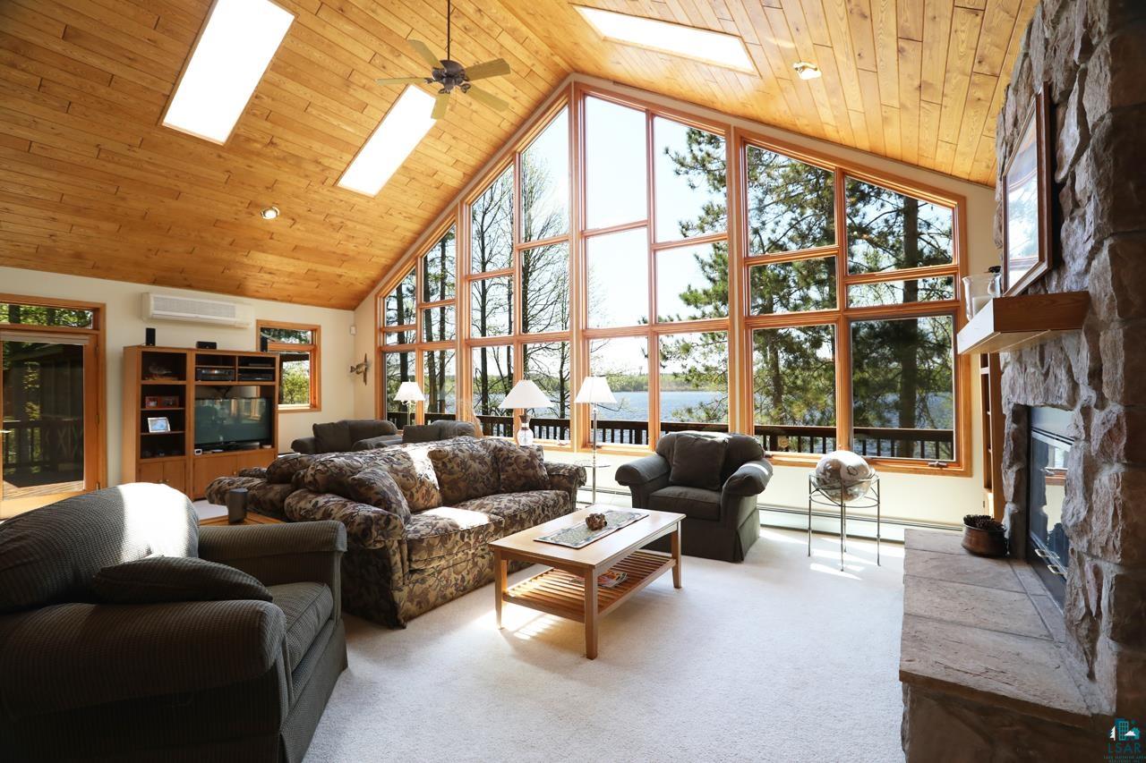 1880 Everett Bay Road Tower, MN 55790 - Photo 4 of 50 Carpeted living room featuring a skylight, high vaulted ceiling, a wall mounted air conditioner, and a fireplace