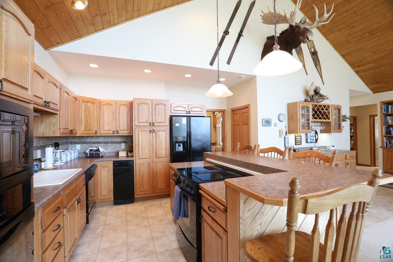 1880 Everett Bay Road Tower, MN 55790 - Photo 6 of 50 Kitchen featuring black appliances, high vaulted ceiling, a kitchen bar, wooden ceiling, and backsplash