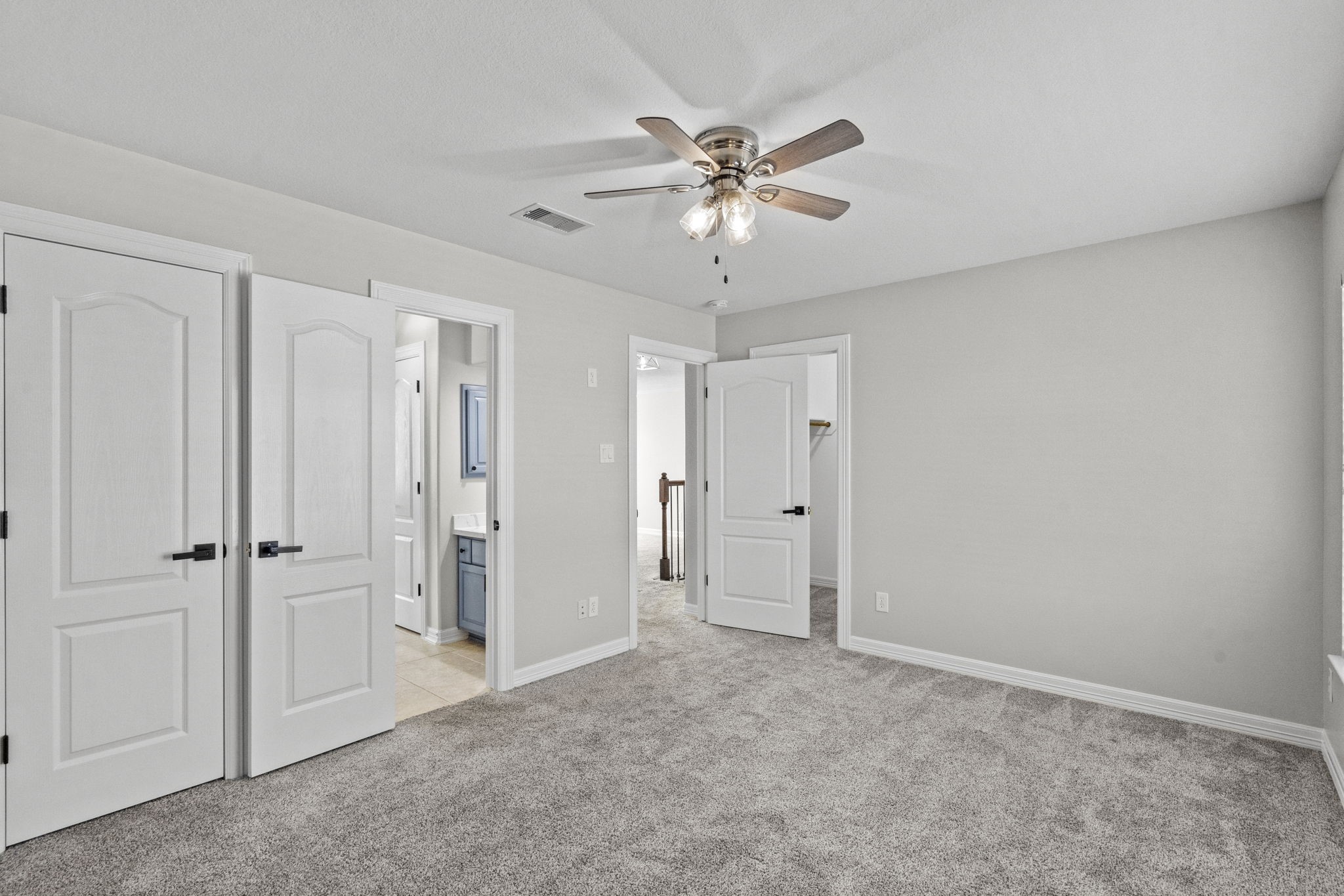 2730 Lawrence Road Kemah, TX 77565 - Photo 37 of 46 This bedroom features soft gray walls, plush carpeting, and a ceiling fan. It includes a walk-in closet and an en-suite bathroom with modern fixtures. The space is bright and inviting, ideal for comfort and relaxation.