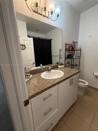 a bathroom with a granite countertop sink a mirror and a toilet