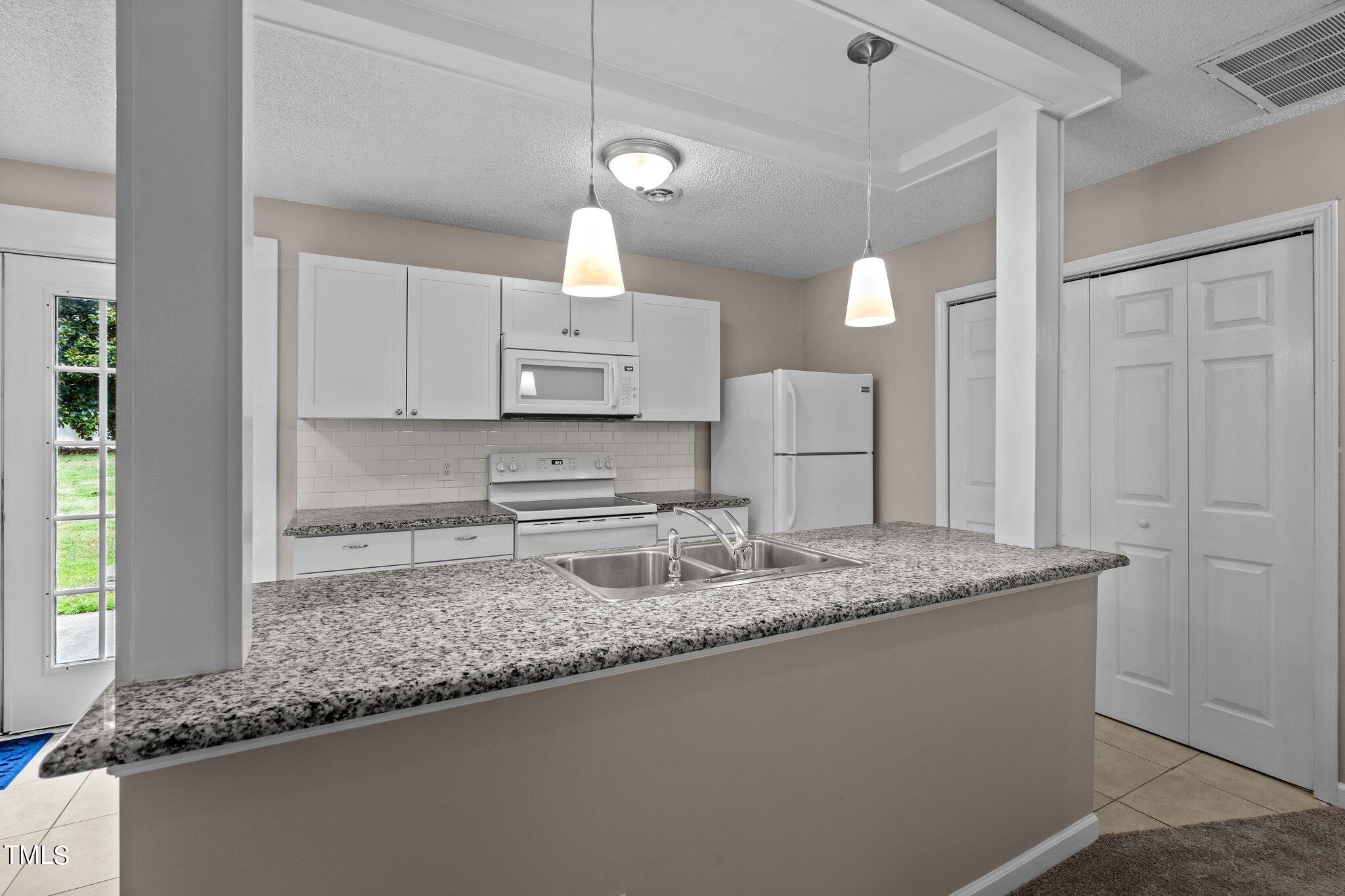 1129 Bermuda Run Knightdale, NC 27545 - Photo 10 of 34 a kitchen with stainless steel appliances granite countertop a sink a oven a refrigerator and white cabinets