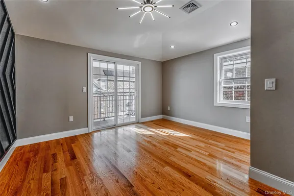 a view of an empty room with window and wooden floor