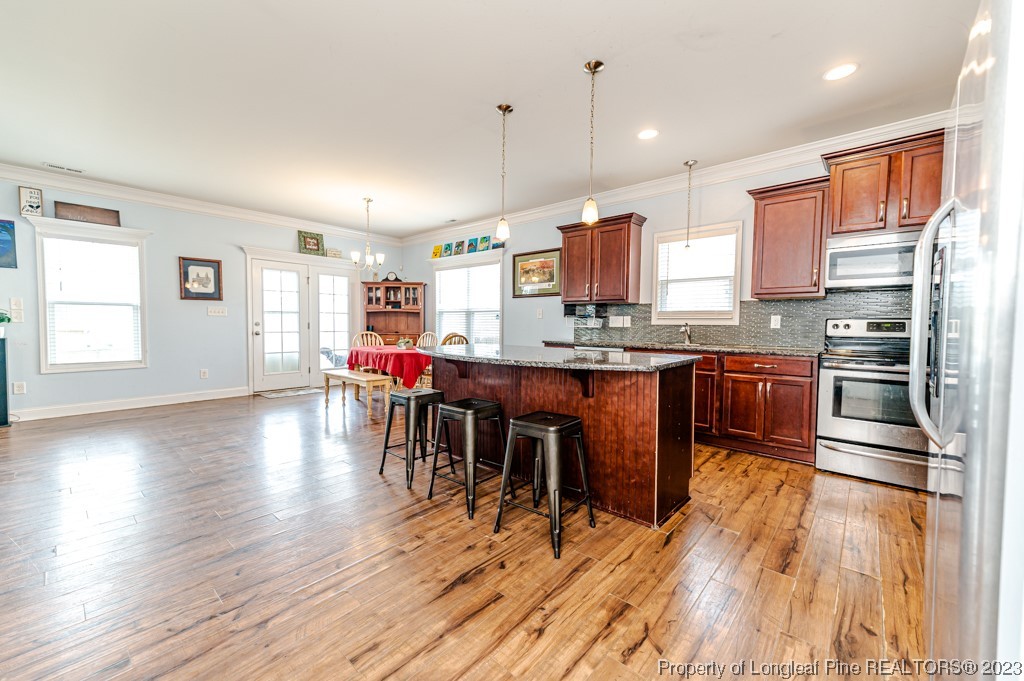 100 Lothian Ln. Cameron, NC 28326 - Photo 14 of 45 a kitchen with stainless steel appliances a dining table chairs and wooden floors