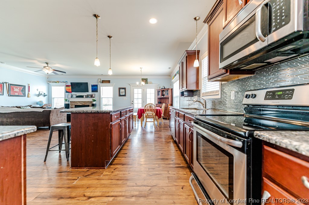100 Lothian Ln. Cameron, NC 28326 - Photo 8 of 45 a kitchen with stainless steel appliances granite countertop a stove top oven a sink dishwasher a dining table and chairs with wooden floor