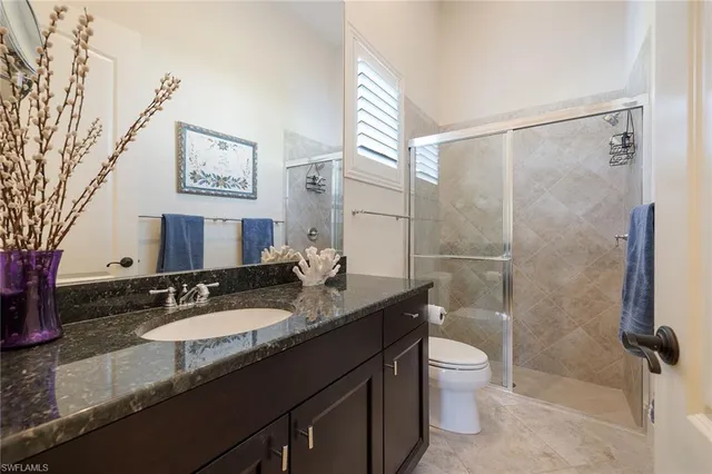 a bathroom with a granite countertop sink toilet a mirror a vanity and shower