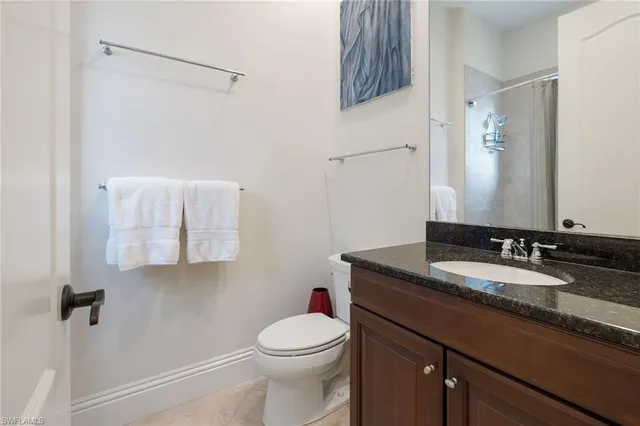 a bathroom with a granite countertop sink mirror vanity and toilet