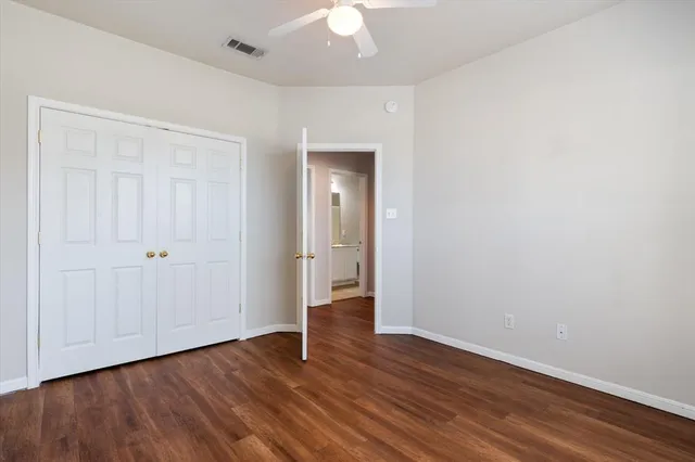 an empty room with wooden floor and a ceiling fan