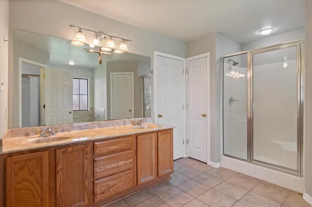 a spacious bathroom with a granite countertop sink a mirror and a shower