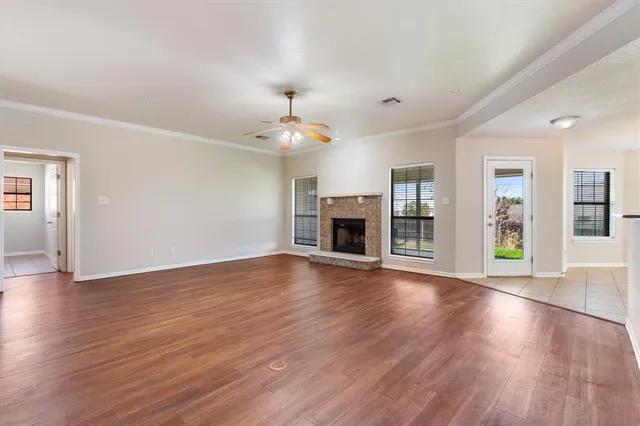 a view of an empty room with wooden floor fireplace and a window