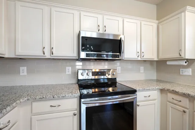 a kitchen with stainless steel appliances granite countertop white cabinets granite counter tops and a wooden floors
