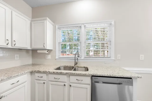 a kitchen with granite countertop white cabinets and a window