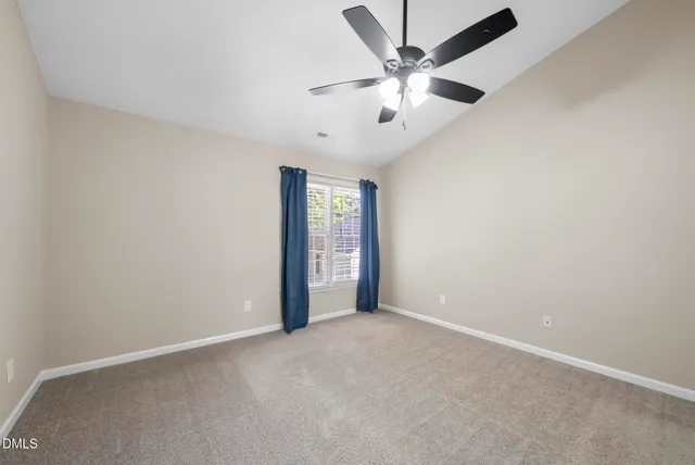 an empty room with chandelier fan and windows