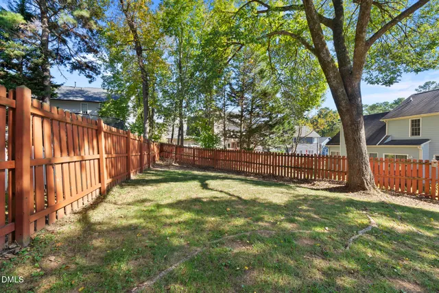 a view of a yard with large trees and wooden fence