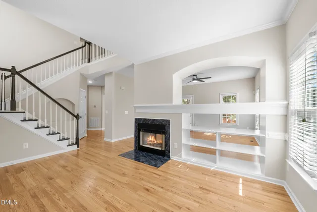a view of an empty room with wooden floor fireplace and a window