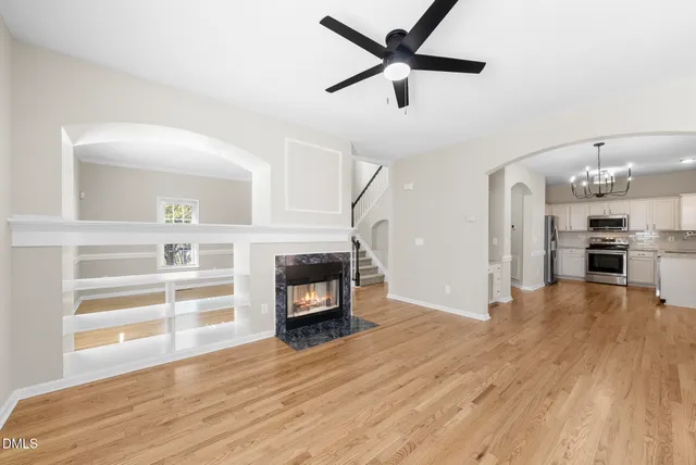 an empty room with wooden floor a fireplace and a kitchen view