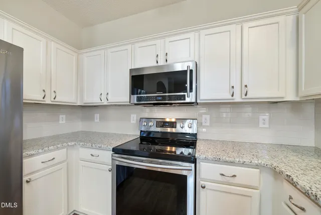 a kitchen with white cabinets and stainless steel appliances