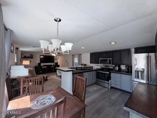 a kitchen with stainless steel appliances kitchen island granite countertop a refrigerator a stove top oven a sink dishwasher and a dining table with wooden floor