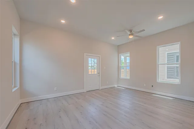 an empty room with wooden floor and windows