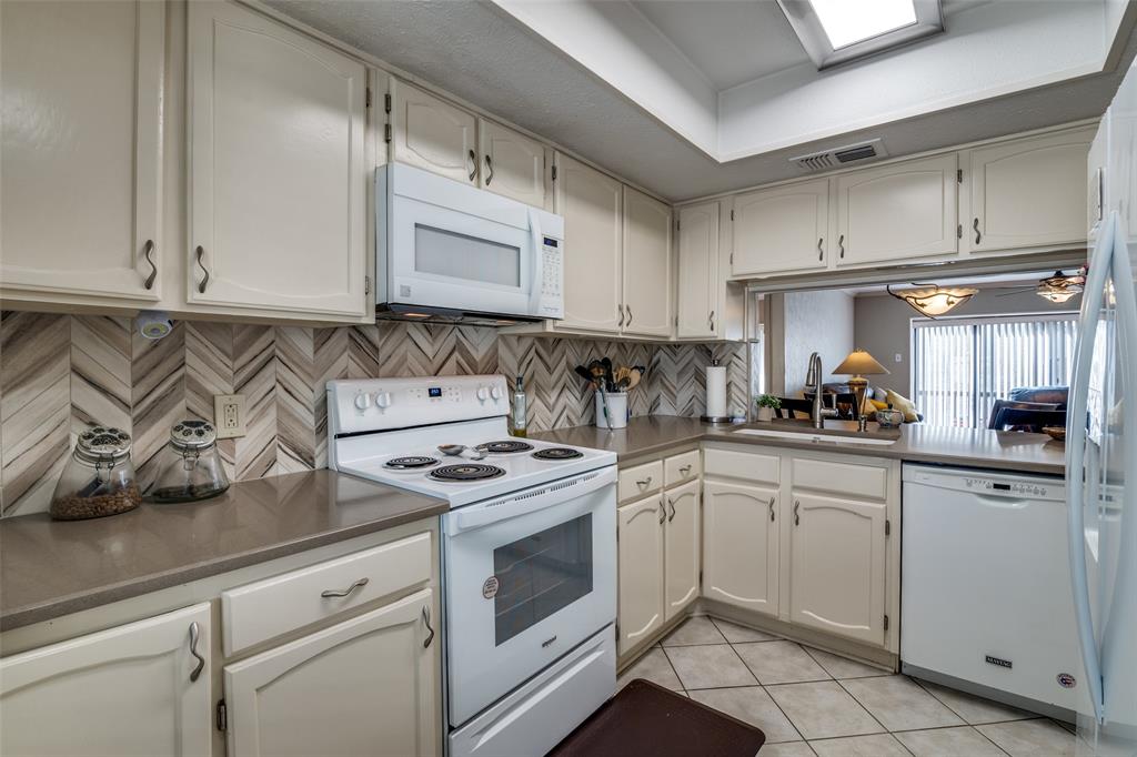4559 North O'Connor Road, Unit 2289 Irving, TX 75062 - Photo 6 of 23 Kitchen with white appliances, a sink, light tile patterned floors, tasteful backsplash, and white cabinetry