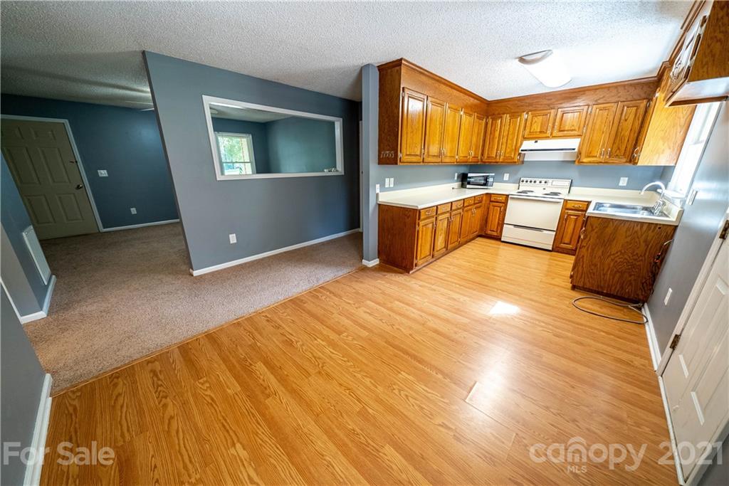 8623 Smith Road Stanfield, NC 28163 - Photo 14 of 27 a kitchen with stainless steel appliances kitchen island granite countertop a stove a sink dishwasher and a microwave with wooden floor