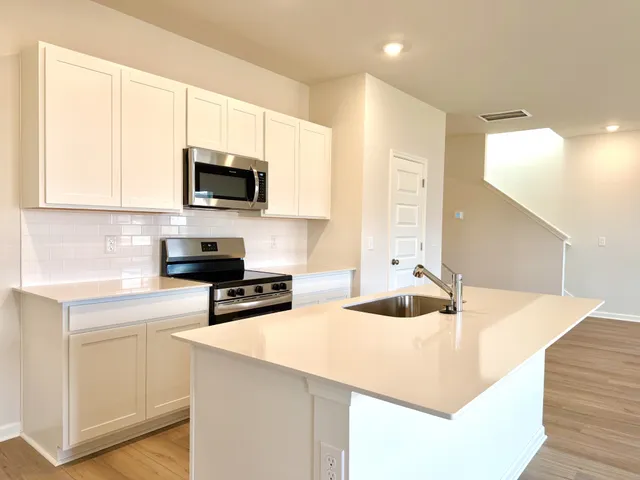 a kitchen with stainless steel appliances a stove a sink a microwave and cabinets