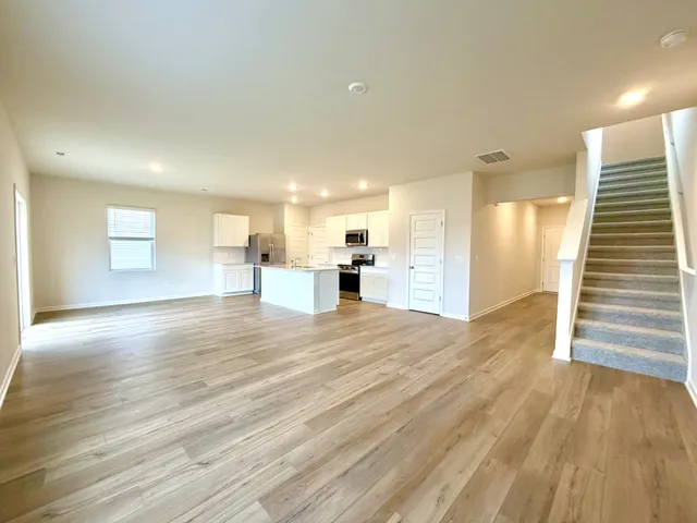 a view of a living room a kitchen with furniture and wooden floor